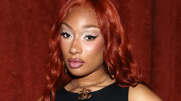 Megan Thee Stallion posing in front of a burgundy curtain